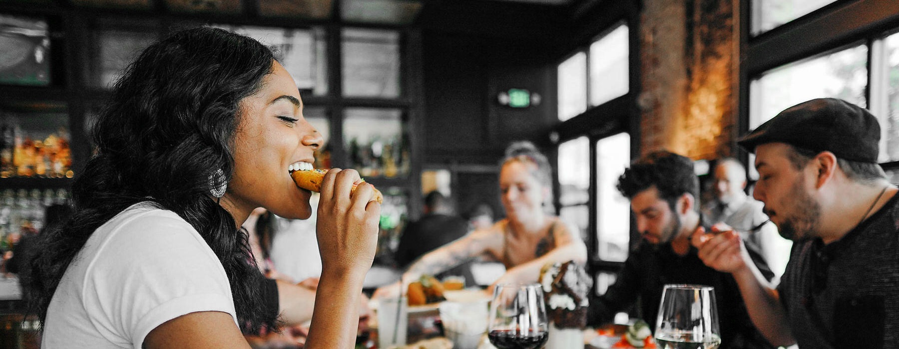 Young woman eating in a local restaurant surrounded by friends